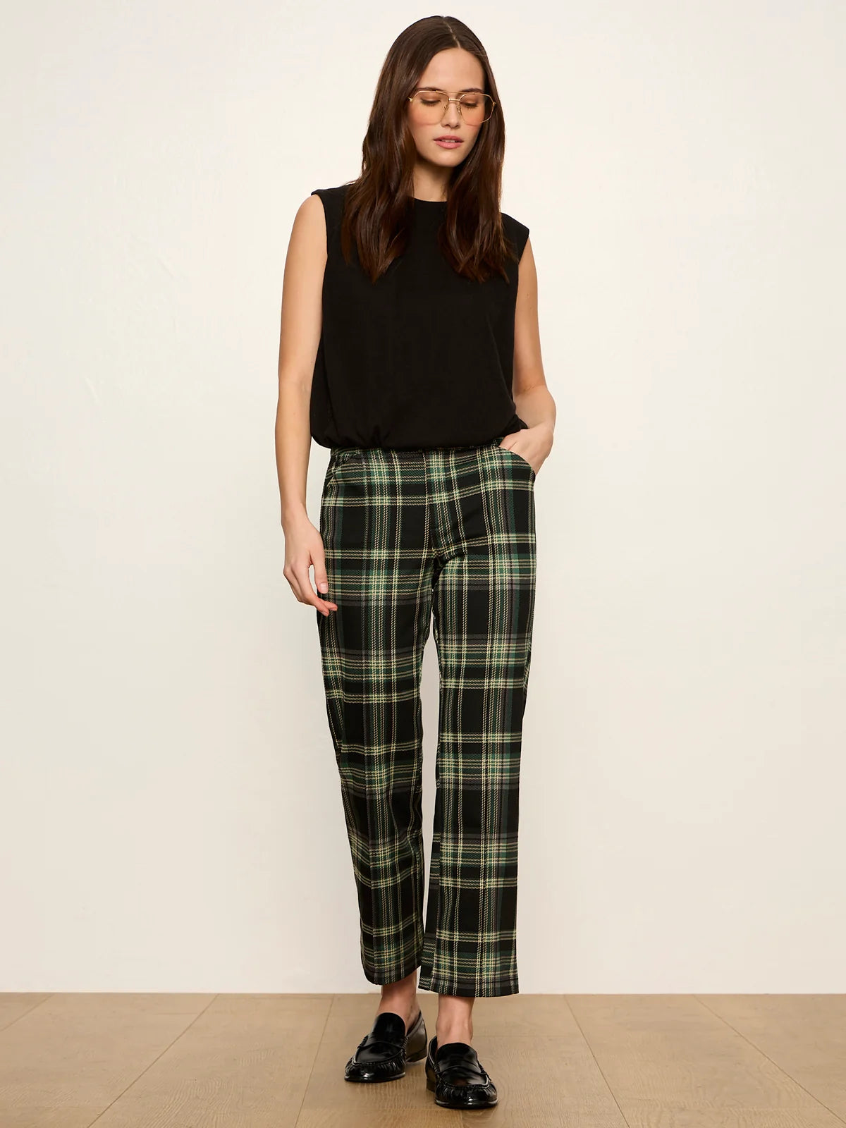 Black sleeveless bubble shell top styled with green plaid trousers and black loafers