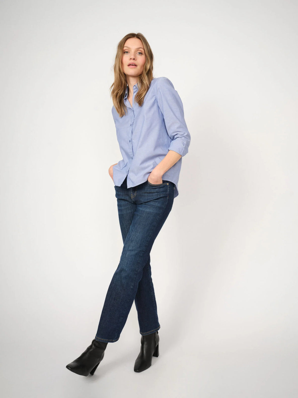 Dark blue straight-leg jeans worn with a light blue shirt and black ankle boots