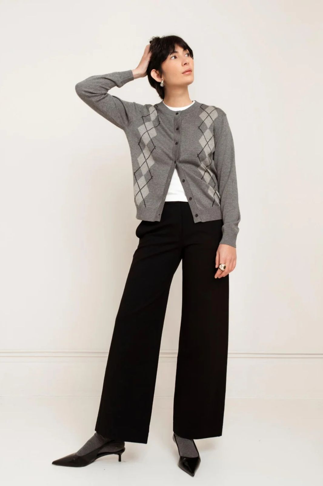 Model wearing black wide-leg Denise Pant with grey argyle cardigan and black kitten heels