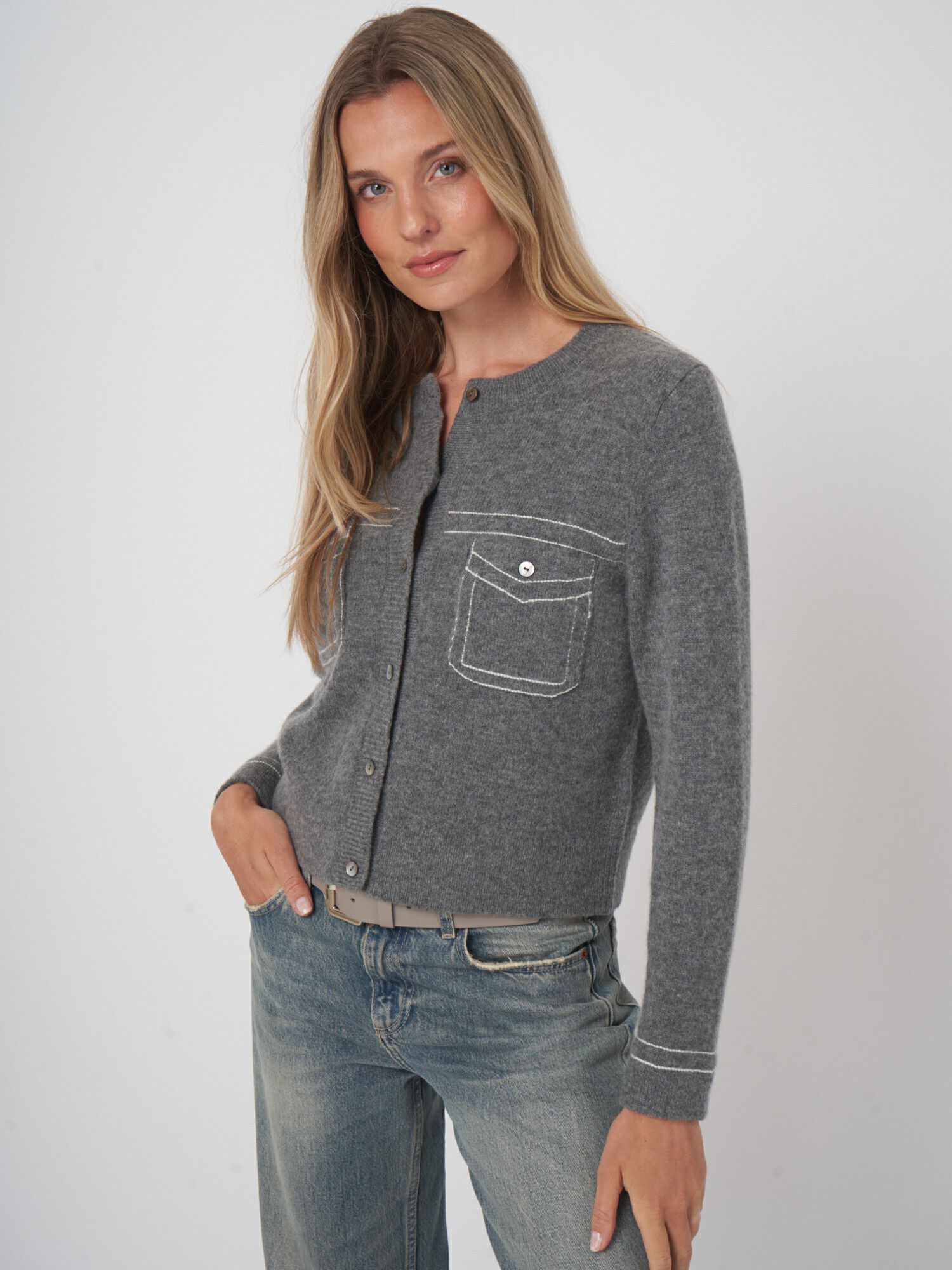 Woman wearing grey wool cashmere cardigan with white contrast stitching and chest pocket