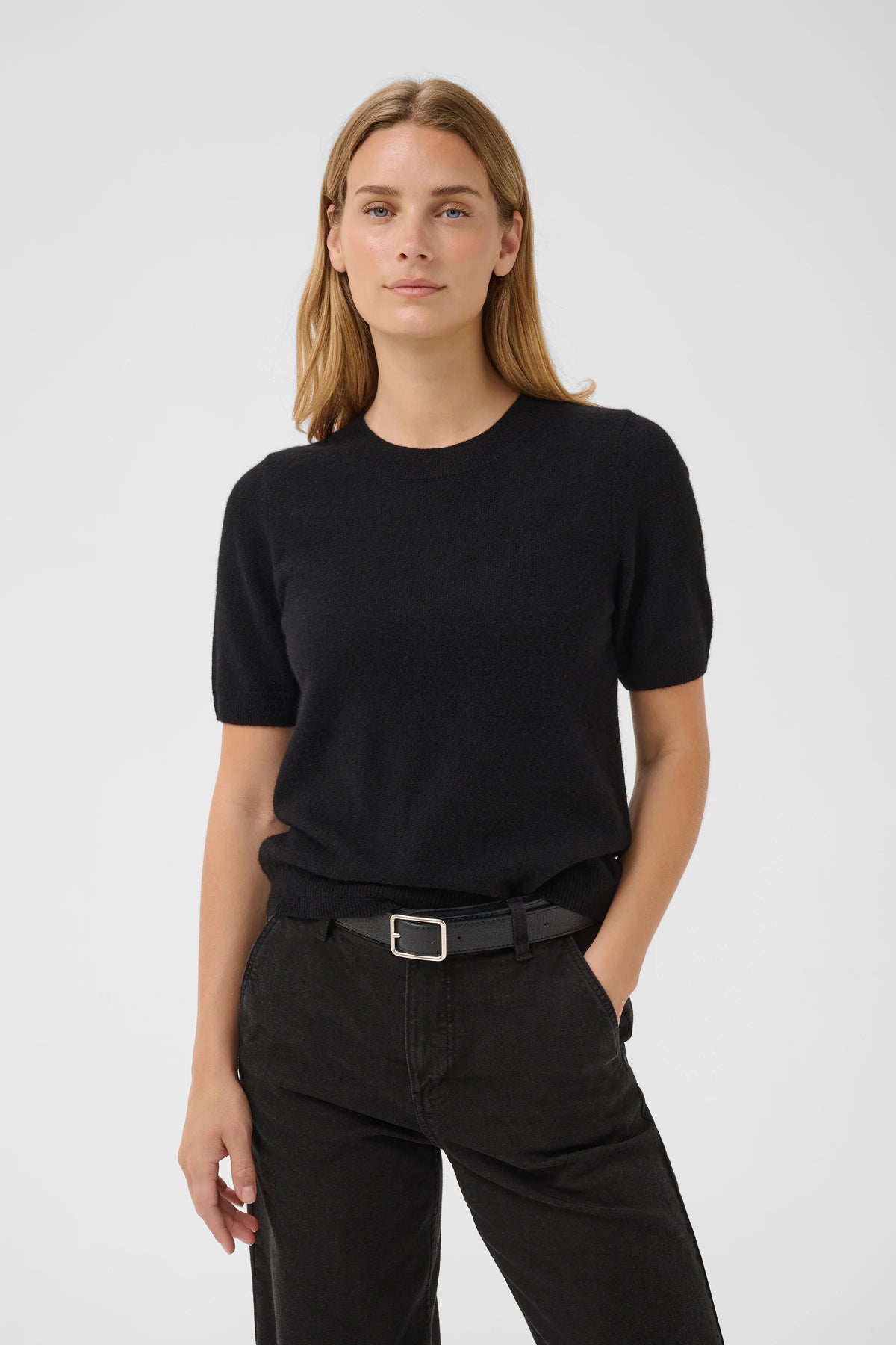 Black short-sleeve knit sweater with crew neck, worn with dark jeans and belt