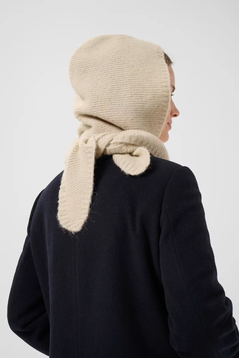Cream knit balaclava hood with tie detail, worn over dark navy coat