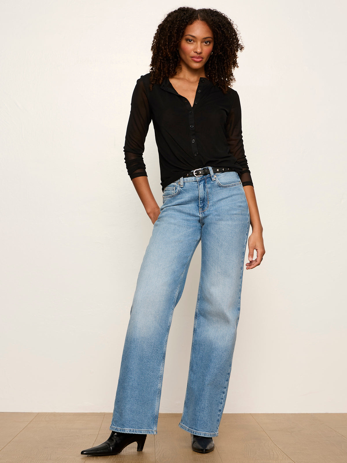 Model wearing Sanctuary black mesh long sleeve cardigan with wide-leg blue jeans and black heels