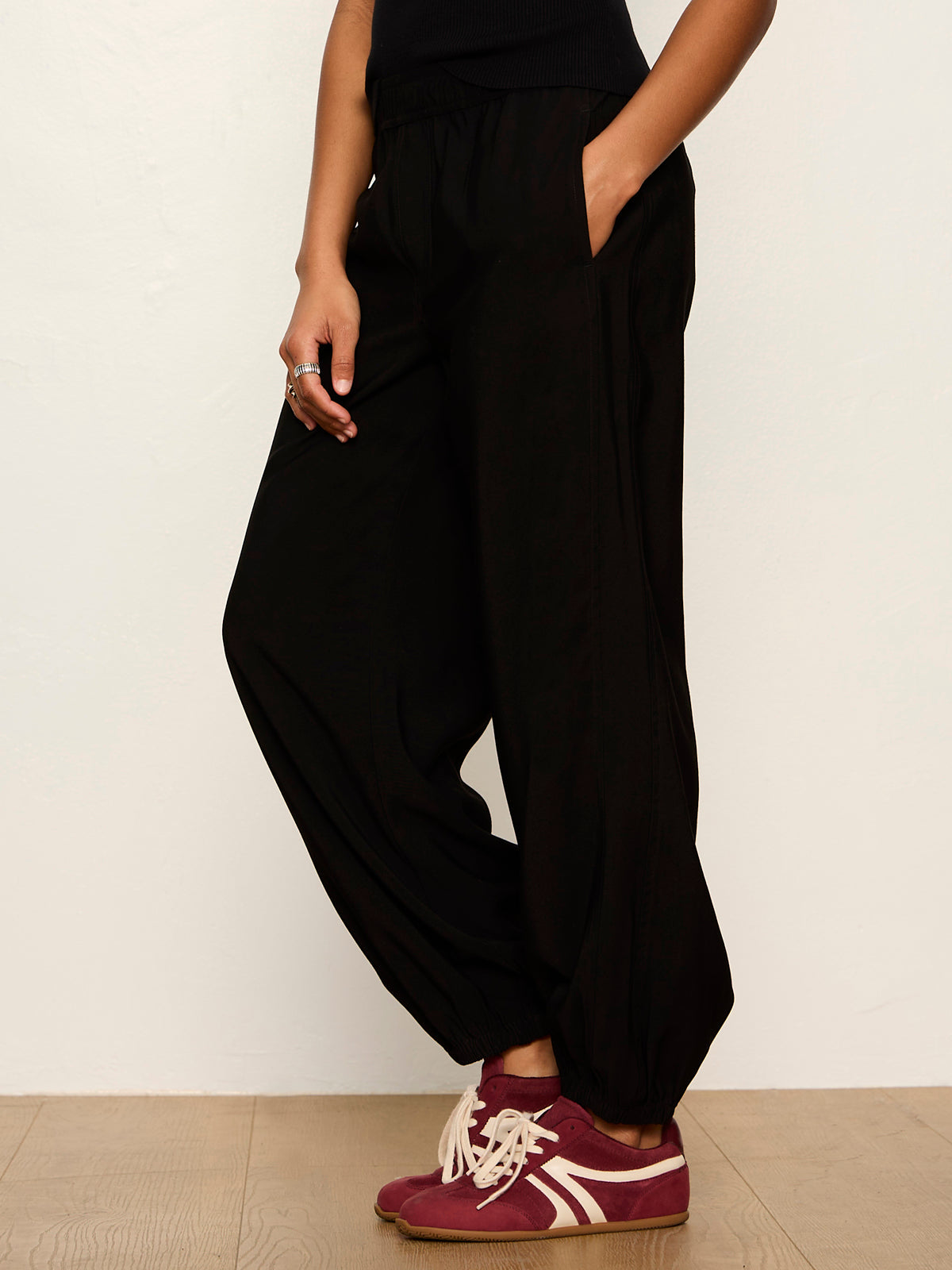 Model wearing black Sanctuary Micro Balloon pants with red sneakers, side view showing relaxed silhouette