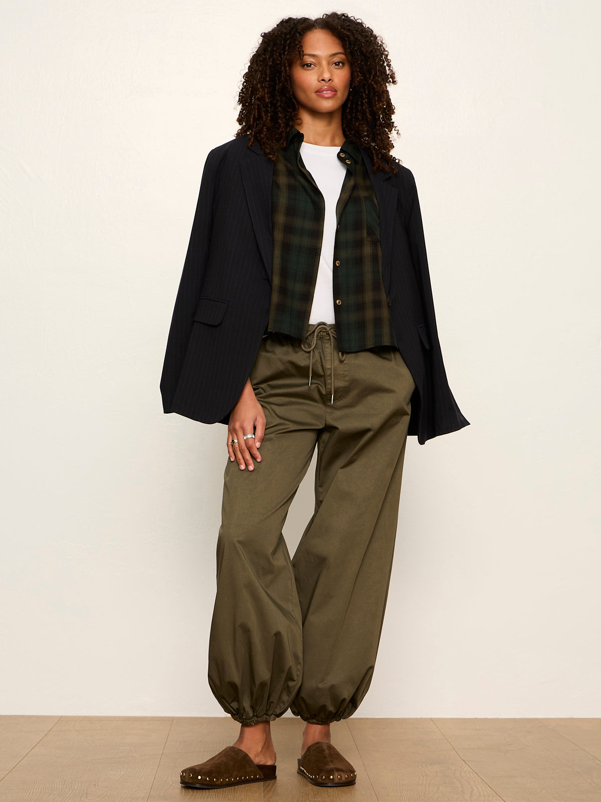 Model wearing Sanctuary Forest Plaid flannel shirt layered under black blazer with olive pants.
