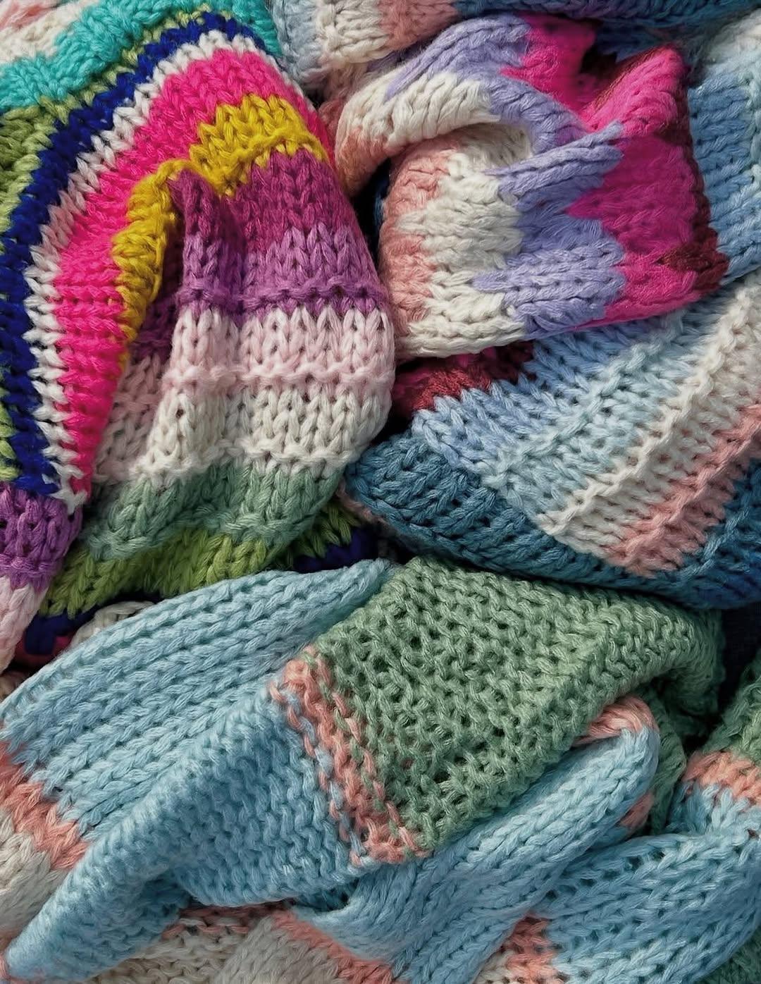 Hand knit striped cardigan in multicolor yarn including pink, blue, purple, and green