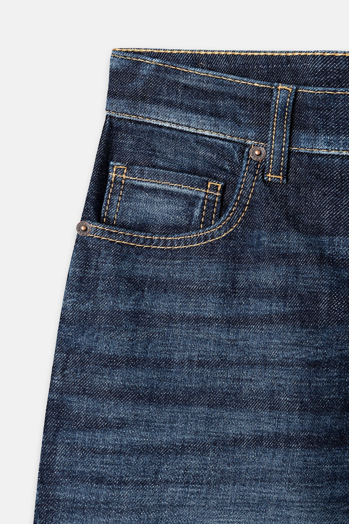 Close-up detail of dark indigo denim jeans showing front pocket with contrast stitching and rivets