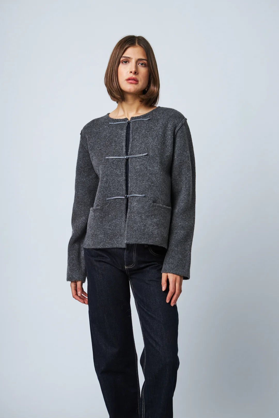 Dark grey knit cardigan with toggle closures and patch pockets, styled with dark jeans