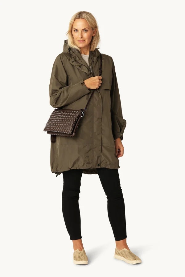 Dark brown woven crossbody bag worn over olive green rain jacket