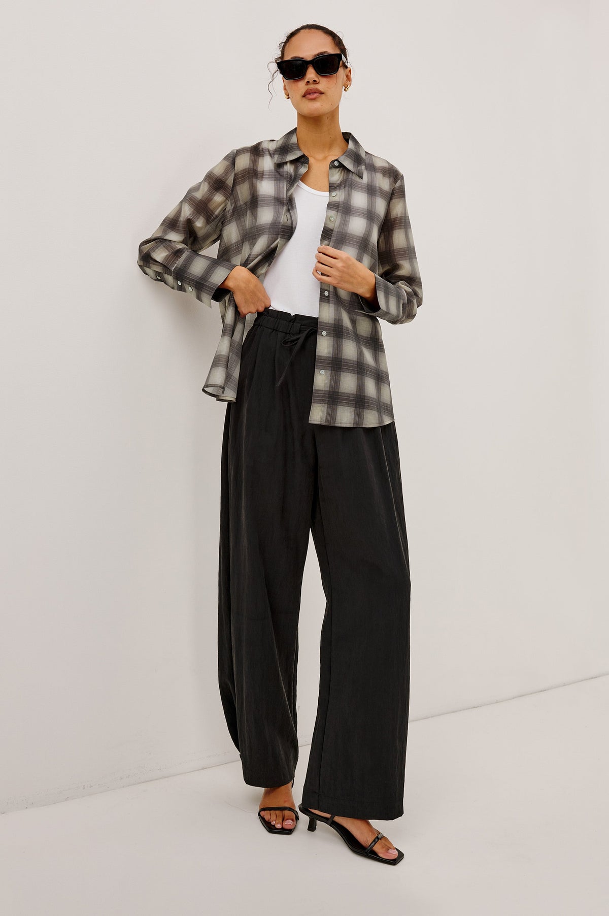 Model wearing Rails Bishop plaid shirt in onyx-taupe colorway with black wide-leg trousers