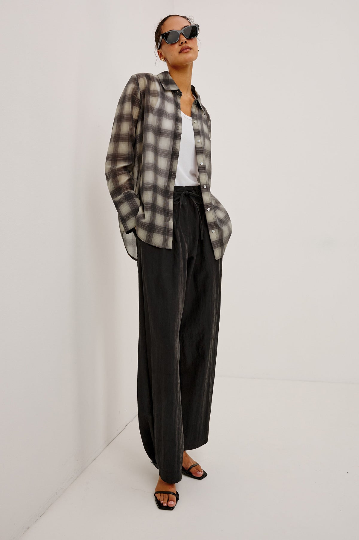 Model wearing Rails Bishop oversized plaid flannel shirt in onyx-taupe colorway with black trousers