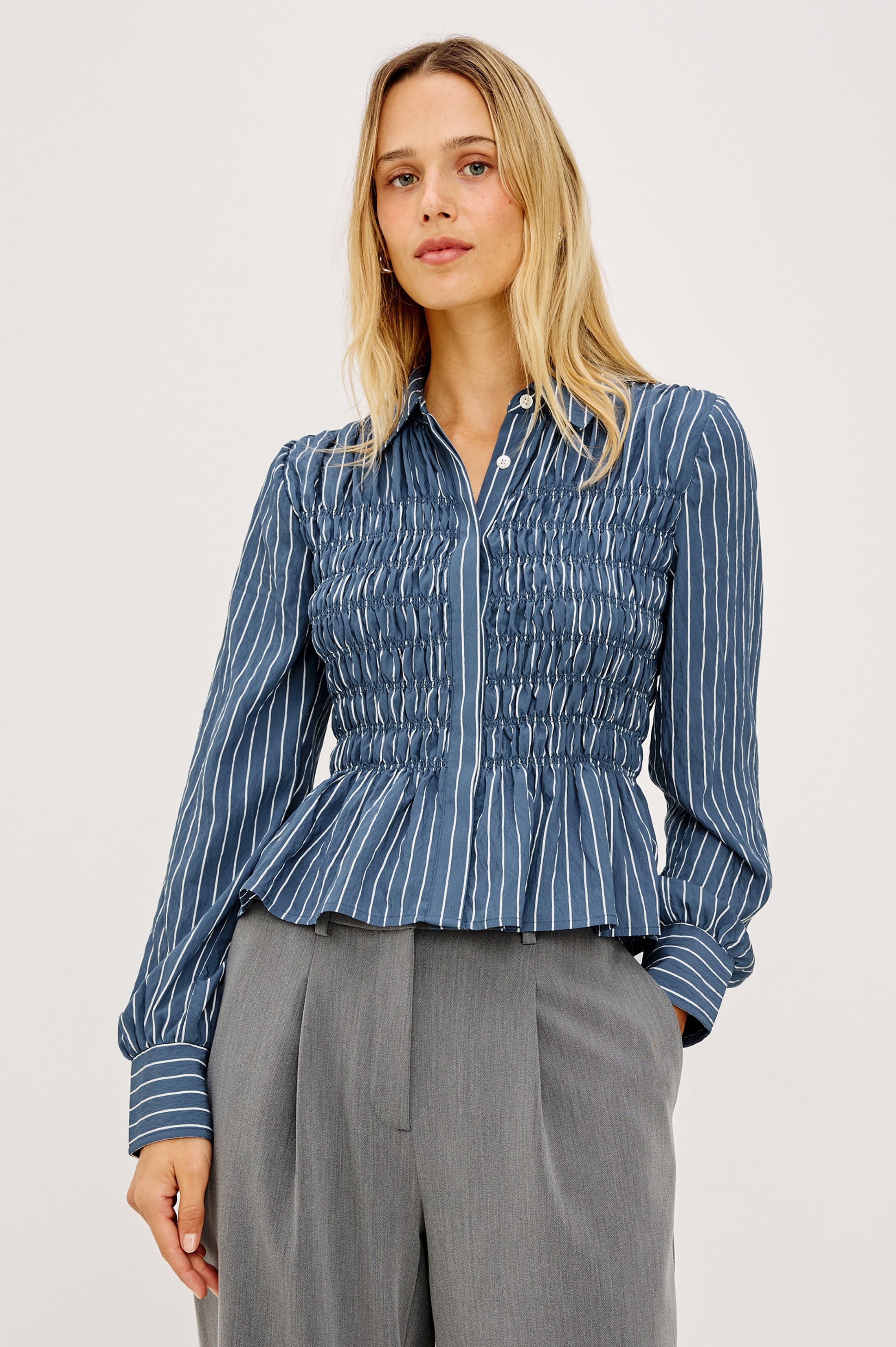 Model wearing Rails smocked striped blue button-down blouse with long sleeves and peplum hem