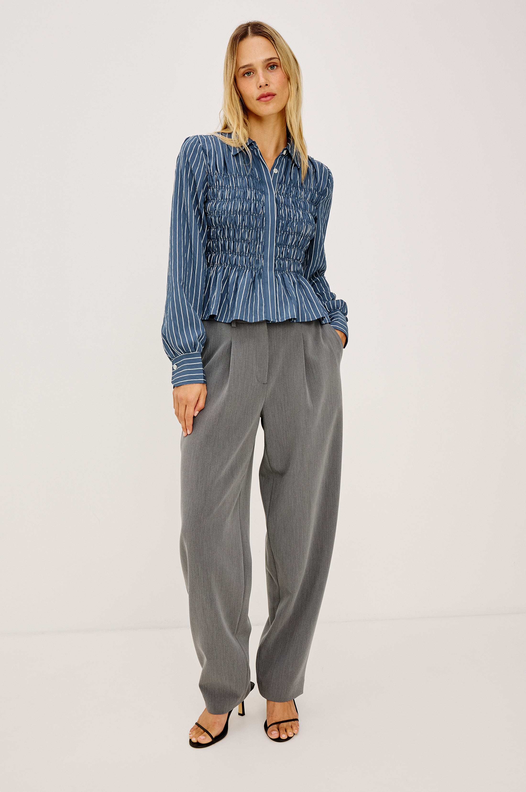 Model wearing Rails smocked blue striped long-sleeve blouse with grey tailored trousers