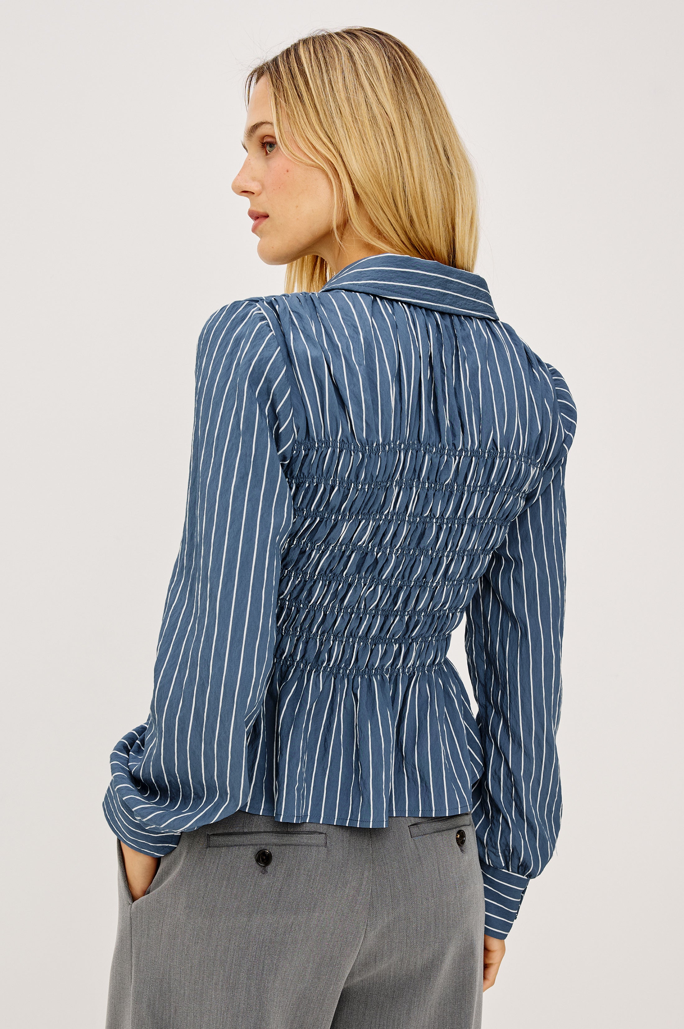 Back view of blue striped smocked blouse with long sleeves and collar detail