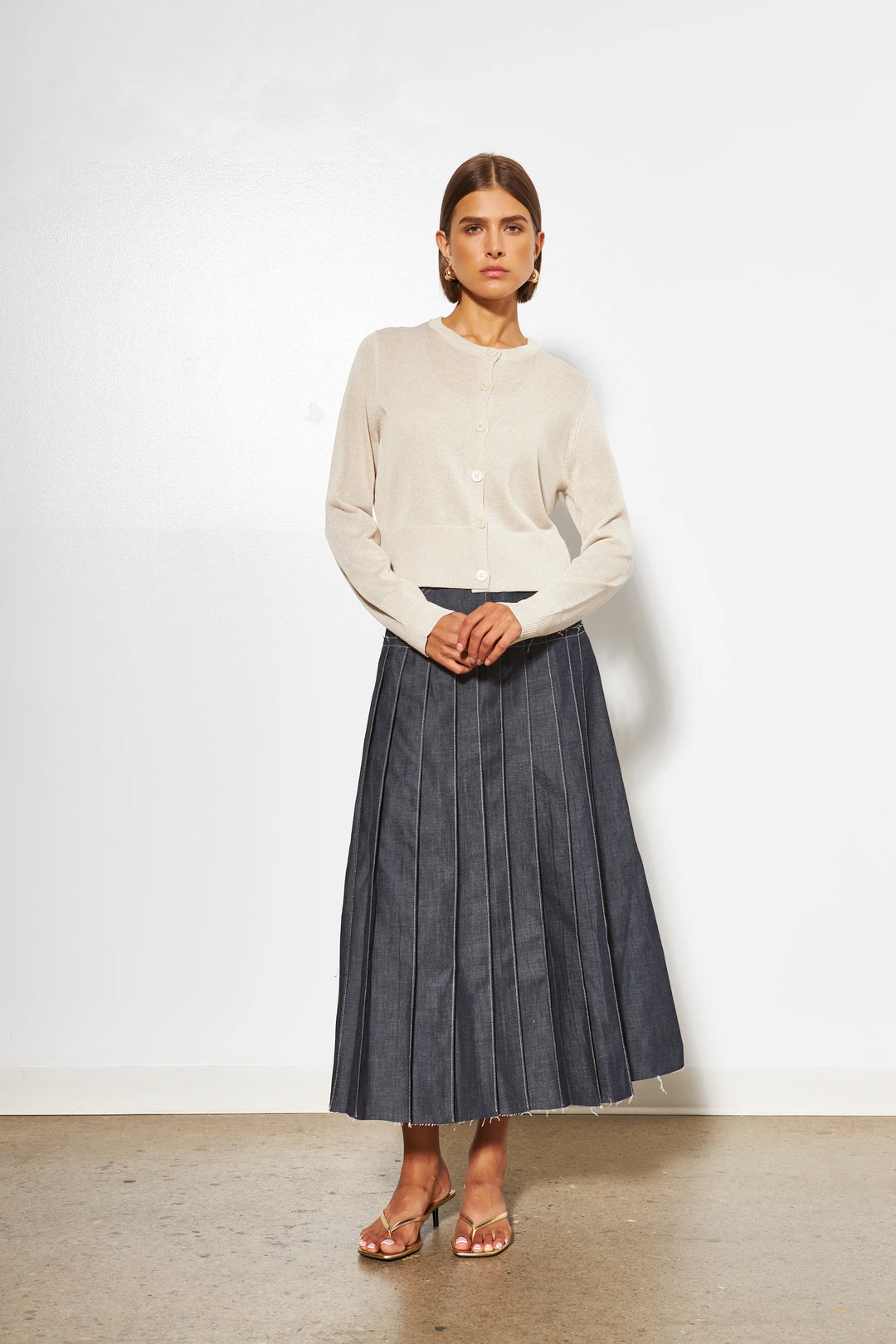 Cream button-front knit cardigan with long sleeves and ribbed hem detail.