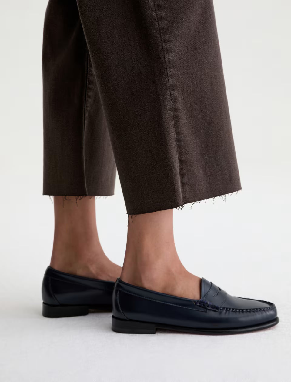 Wide leg cropped dark brown jeans with raw hem, styled with navy loafers
