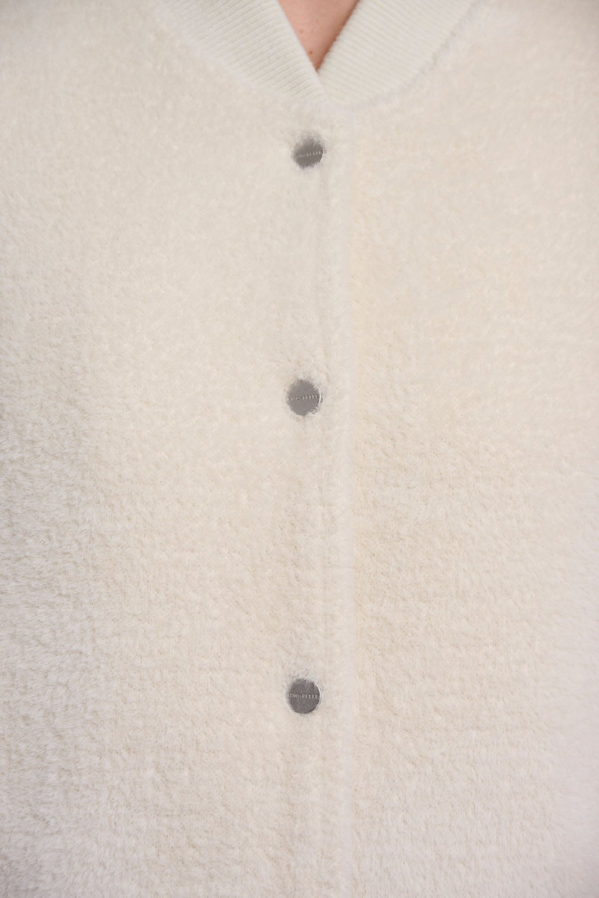 Close-up detail of RINO & PELLE FELIX cardigan in Birch showing silver snap buttons and textured boucle fabric