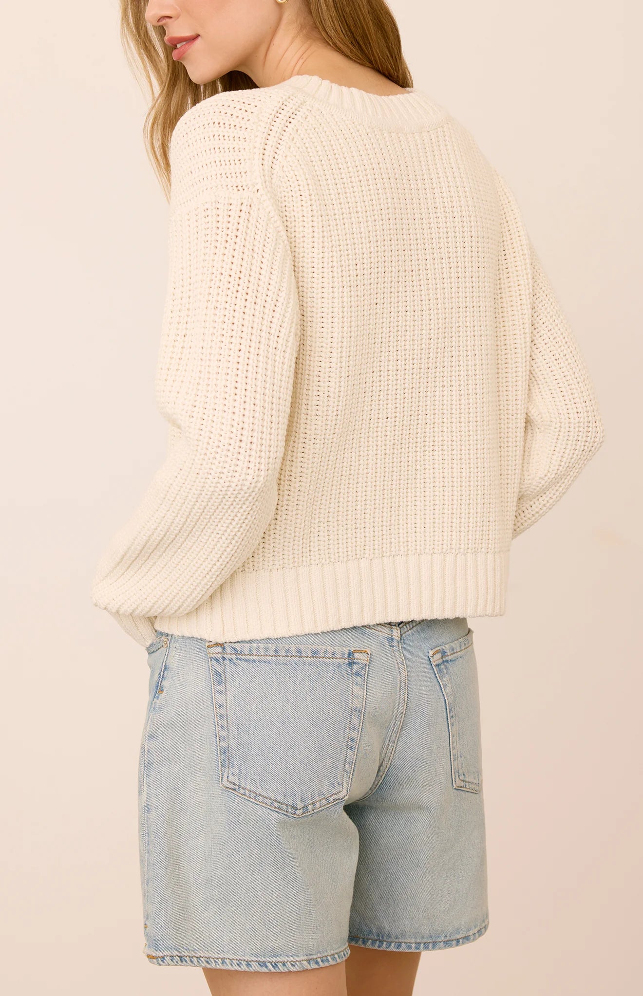 Gentle Fawn Jocelyn cream chunky knit sweater paired with light wash denim shorts, back view