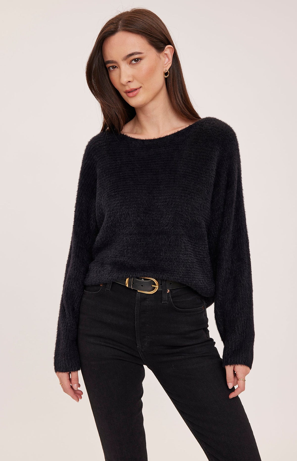 Woman wearing Gentle Fawn Mara black fuzzy knit sweater with dark jeans and belt