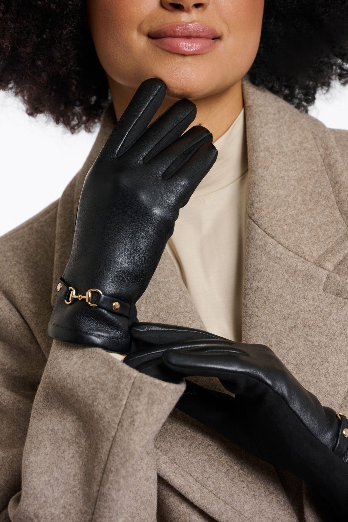 Model wearing black leather gloves with gold horsebit hardware detail on wrist