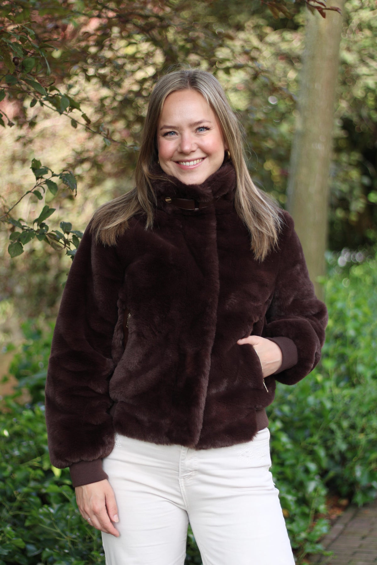 Woman smiling outdoors wearing Rino & Pelle Ambra faux fur jacket in deep chocolate brown
