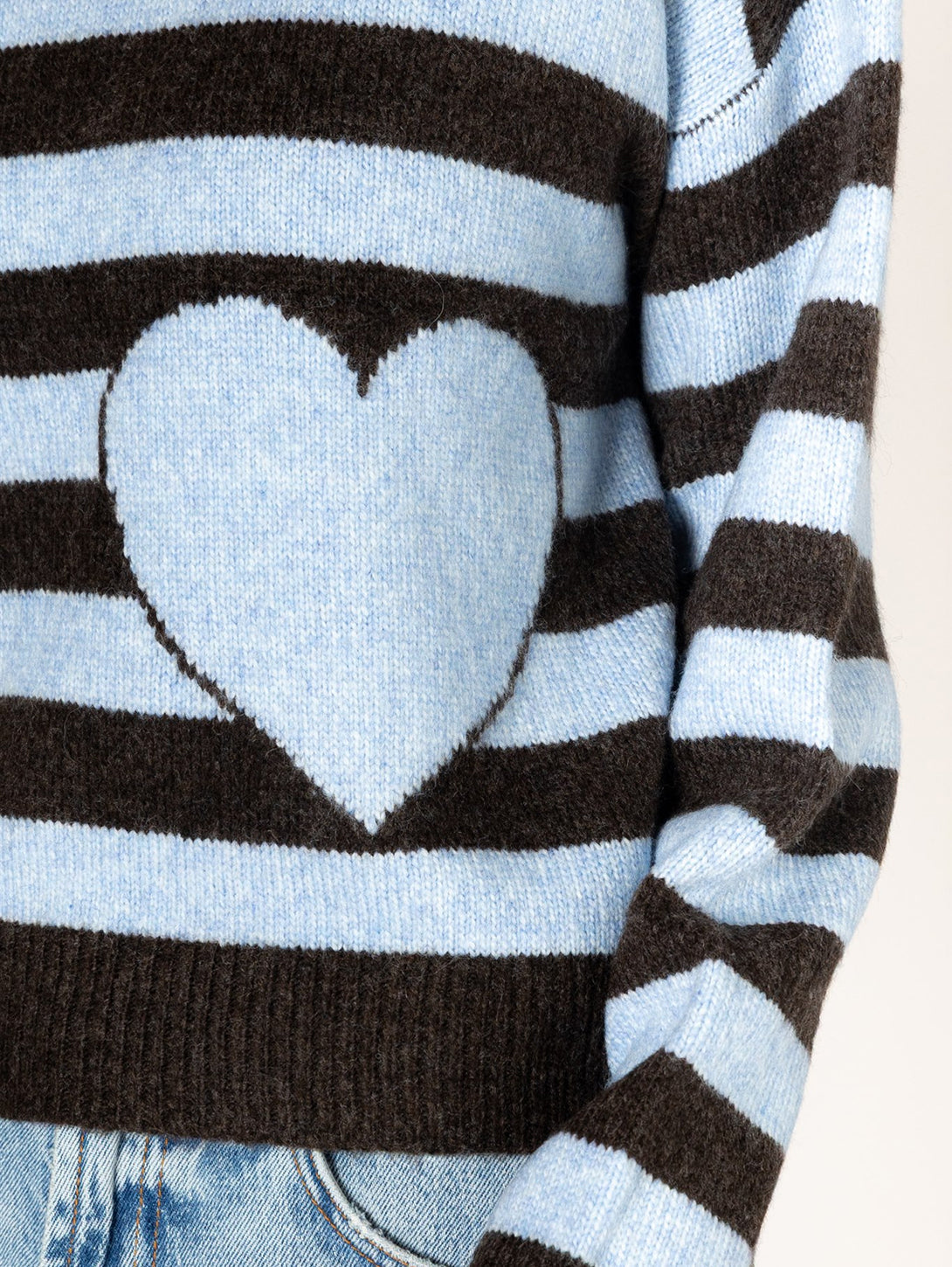 Close-up detail of blue and brown striped knit sweater with intarsia heart design on front