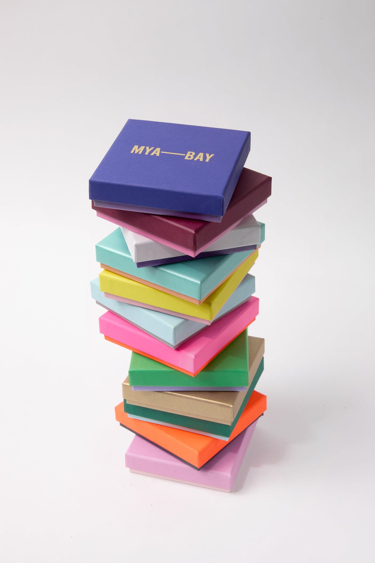 Stack of colorful MYA-BAY jewelry gift boxes with gold branding on top