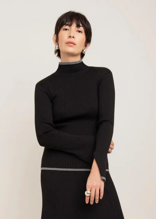 Black ribbed knit turtleneck sweater with contrast grey metallic trim at collar and cuffs
