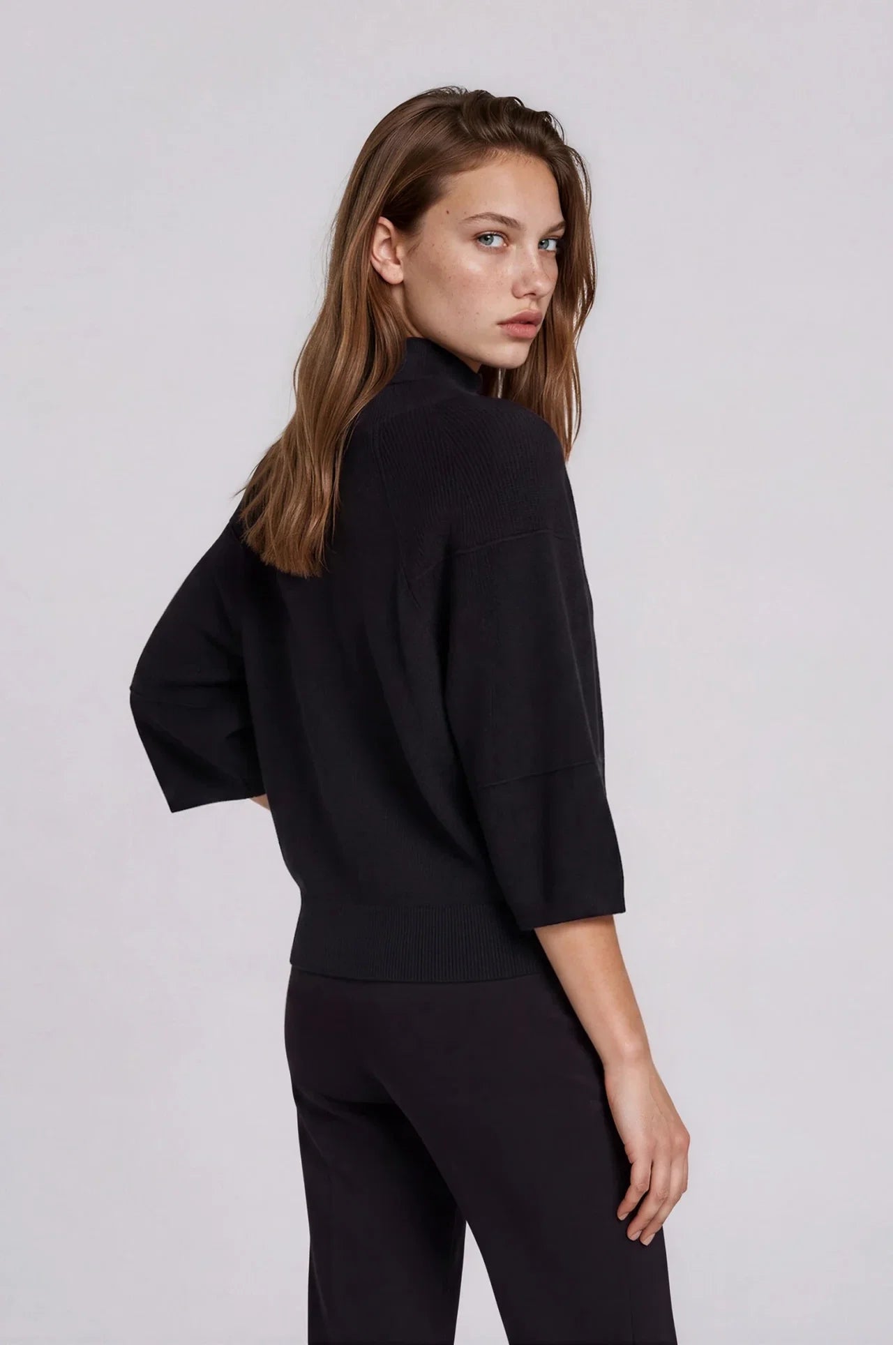 Black knit turtleneck sweater with 3/4 sleeves and relaxed boxy fit, back view