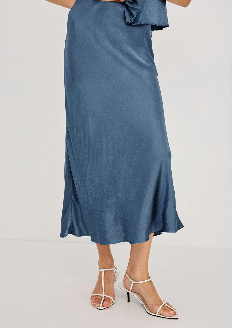 Rails Anya dusty blue satin midi skirt with flared hem, worn with white heeled sandals