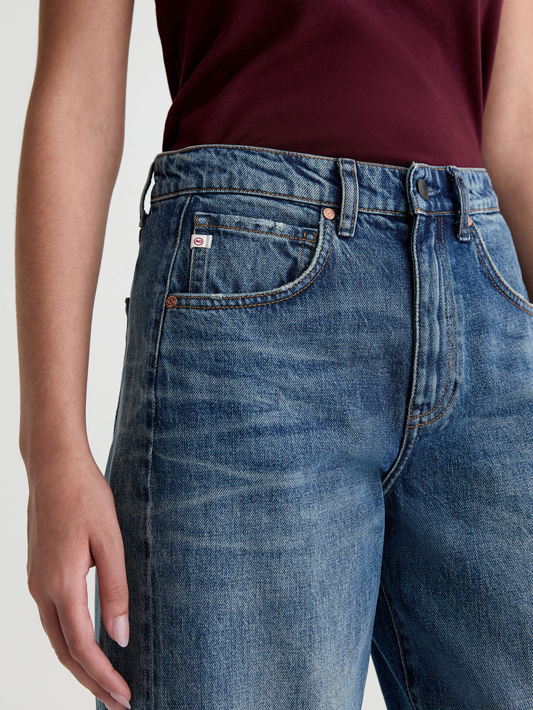 Close-up detail of AG Hattie jeans in 10 Yrs Front Line medium blue wash showing waistband and pocket