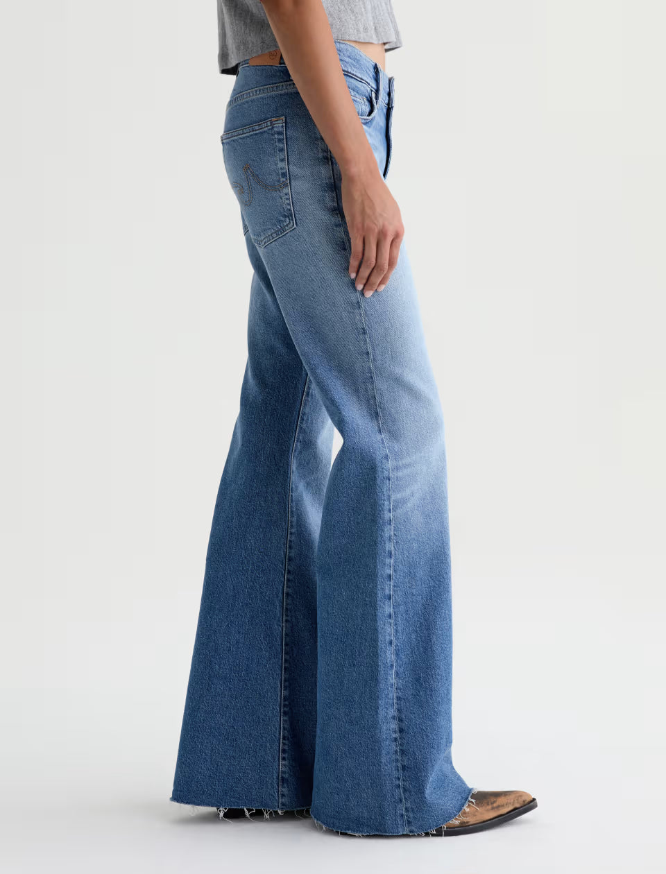 AG wide-leg flare jeans in medium blue wash with raw hem, side view