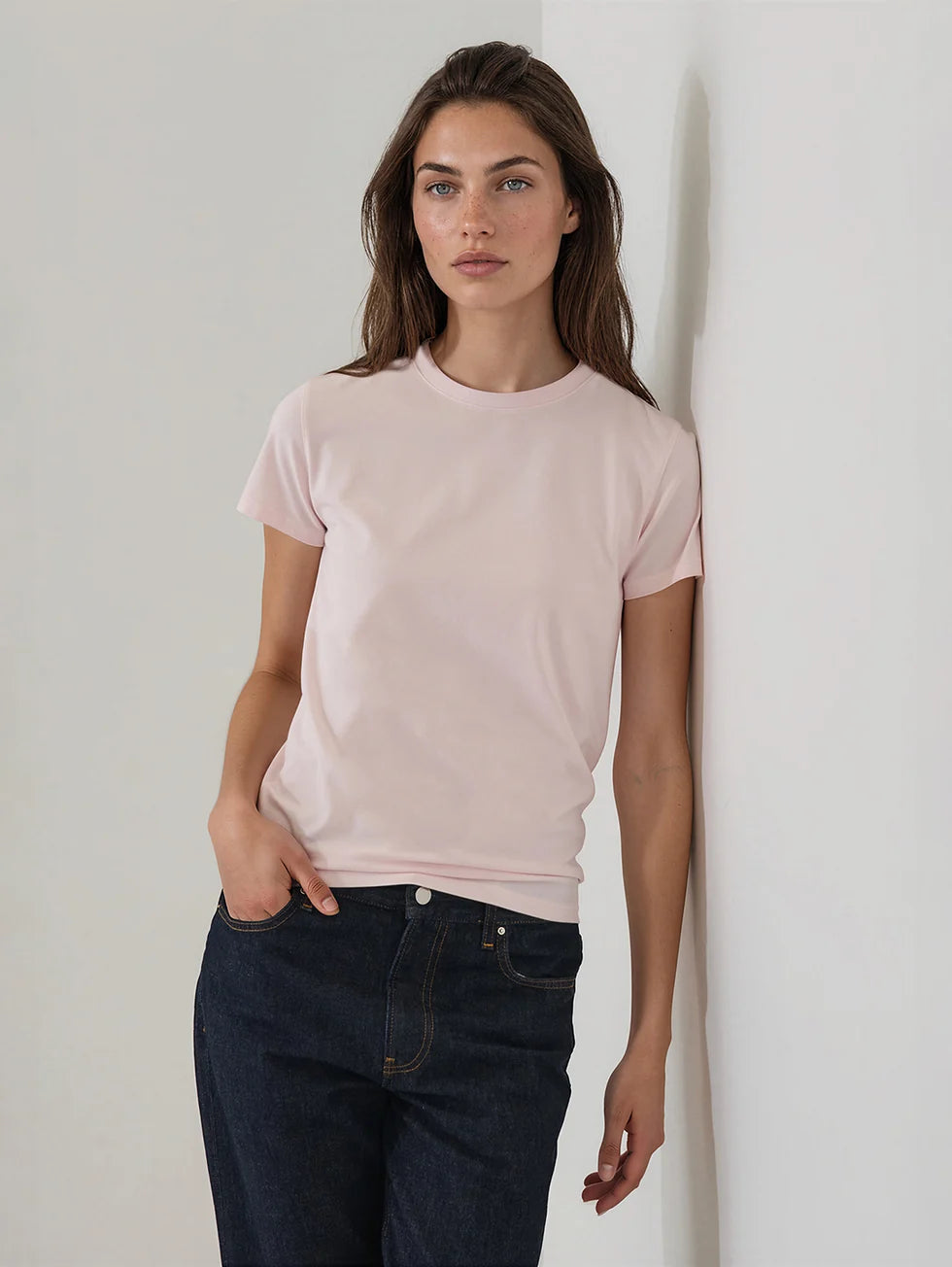 Fitted pale pink short-sleeve crew neck T-shirt worn with dark navy jeans