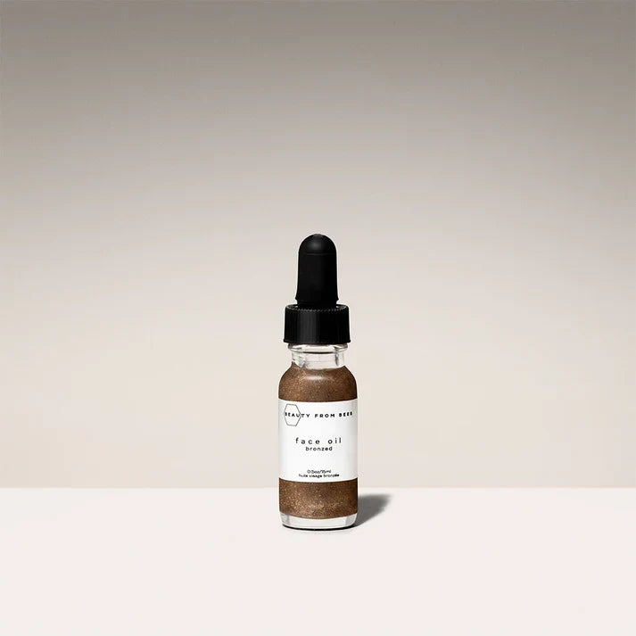 Small glass dropper bottle of bronzed face oil with shimmer by Beauty From Bees