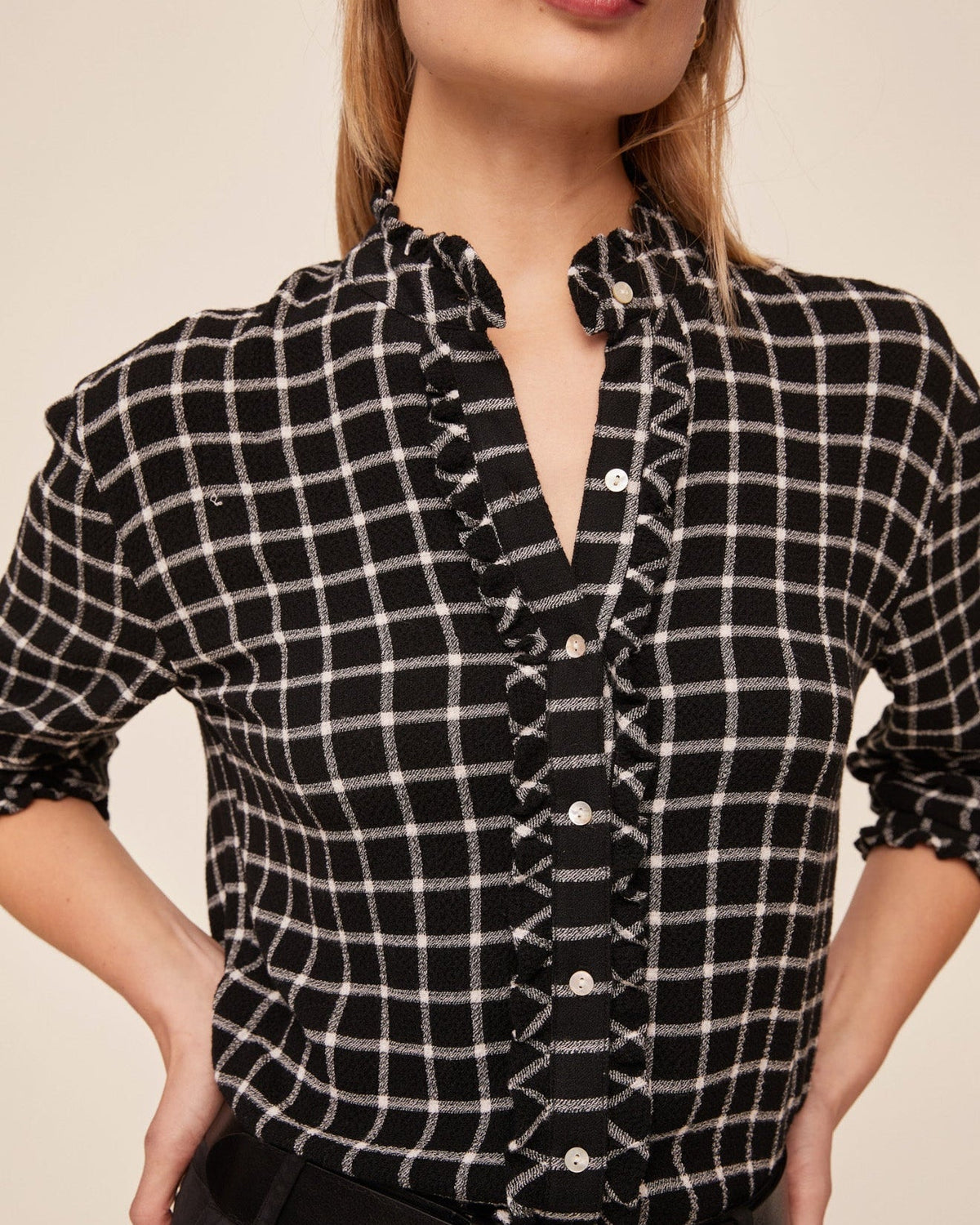 Close-up detail of black and white plaid button-down shirt with ruffle trim edges