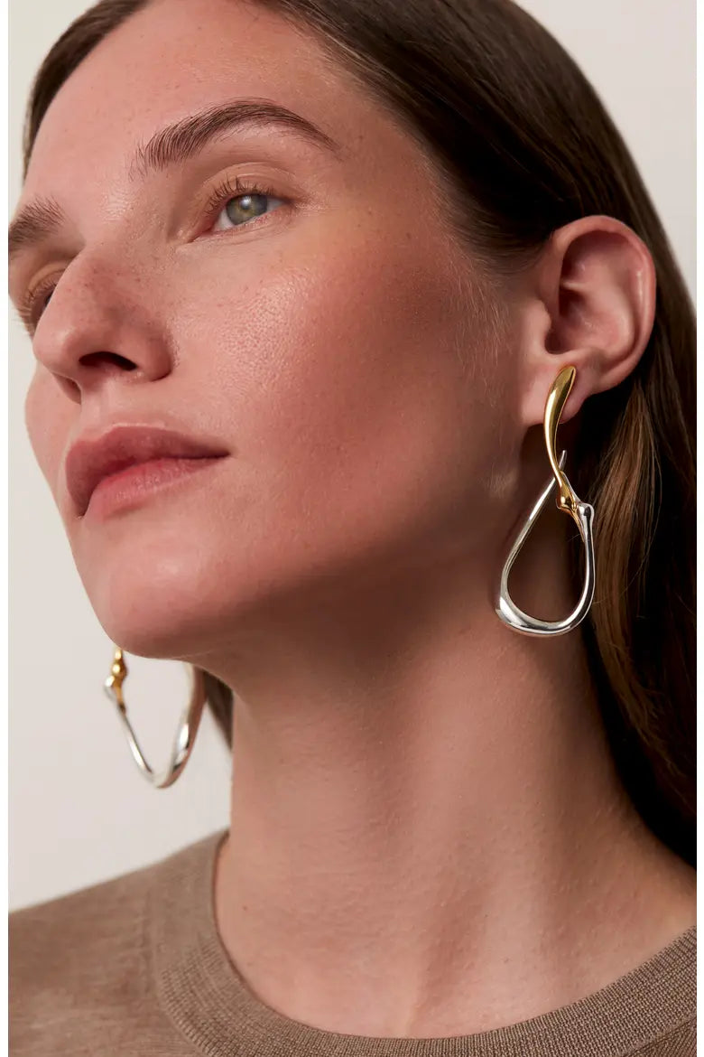 Large two-tone silver and gold irregular hoop earrings worn by a model