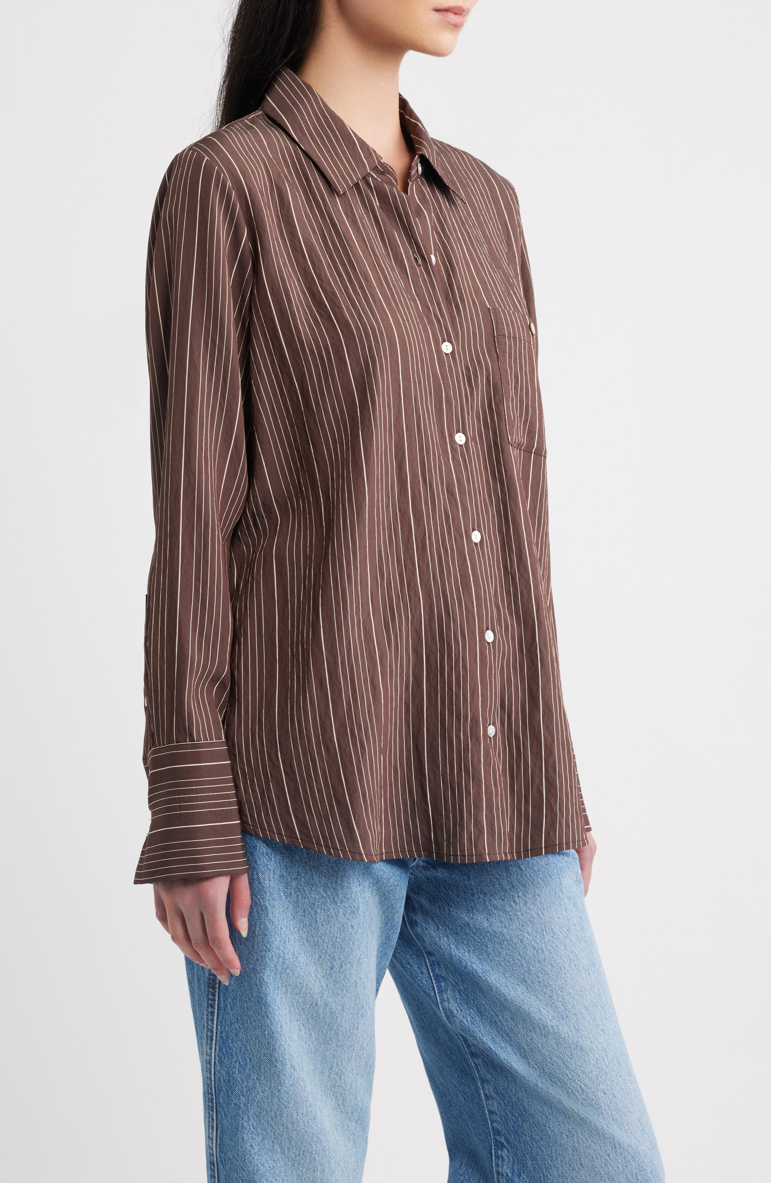 Model wearing Rails Beck oversized button-down shirt in hickory indigo stripe with blue jeans, side view
