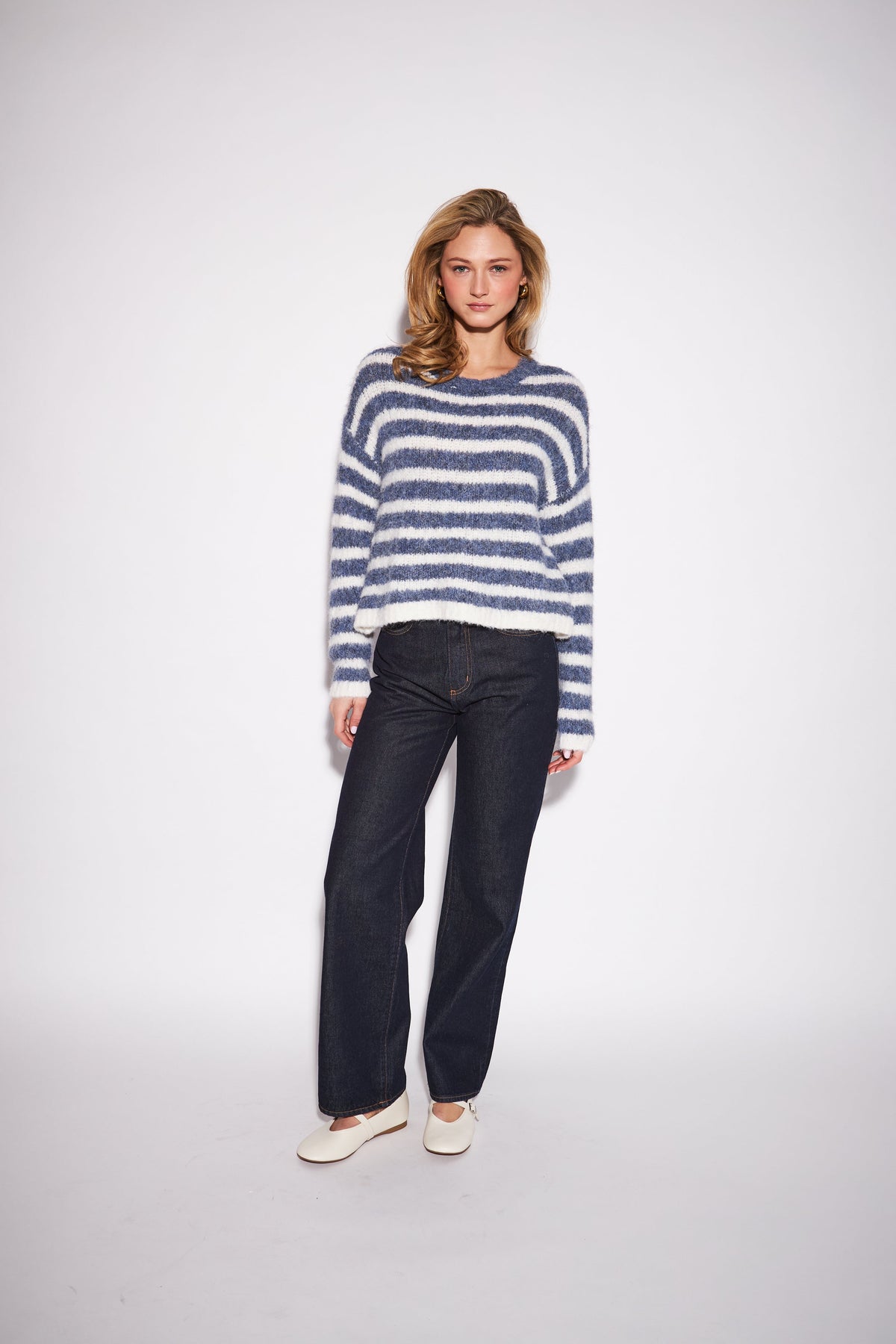 Model wearing John & Jenn Carmen fuzzy striped sweater in blue and white denim fade colorway with dark jeans