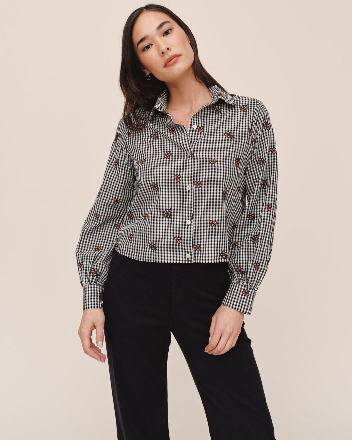 Model wearing Bella Dahl long sleeve crop button down in micro floral gingham pattern with black trousers