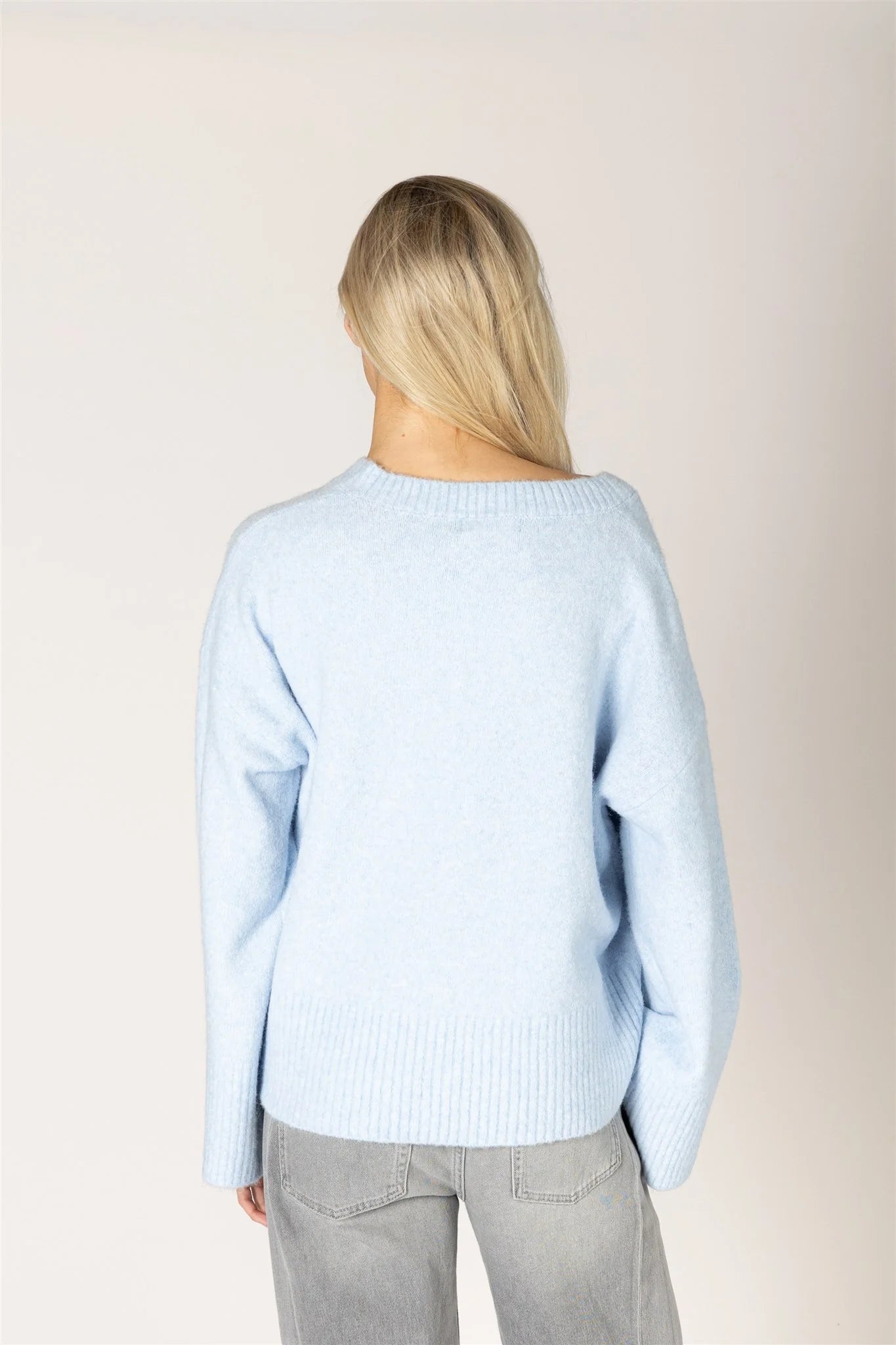 Light blue oversized knit sweater with ribbed hem and wide neckline, back view