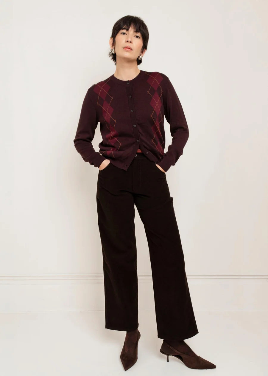 Model wearing Paper Label Helly Argyle Cardigan in chocolate with wide-leg trousers, front view.