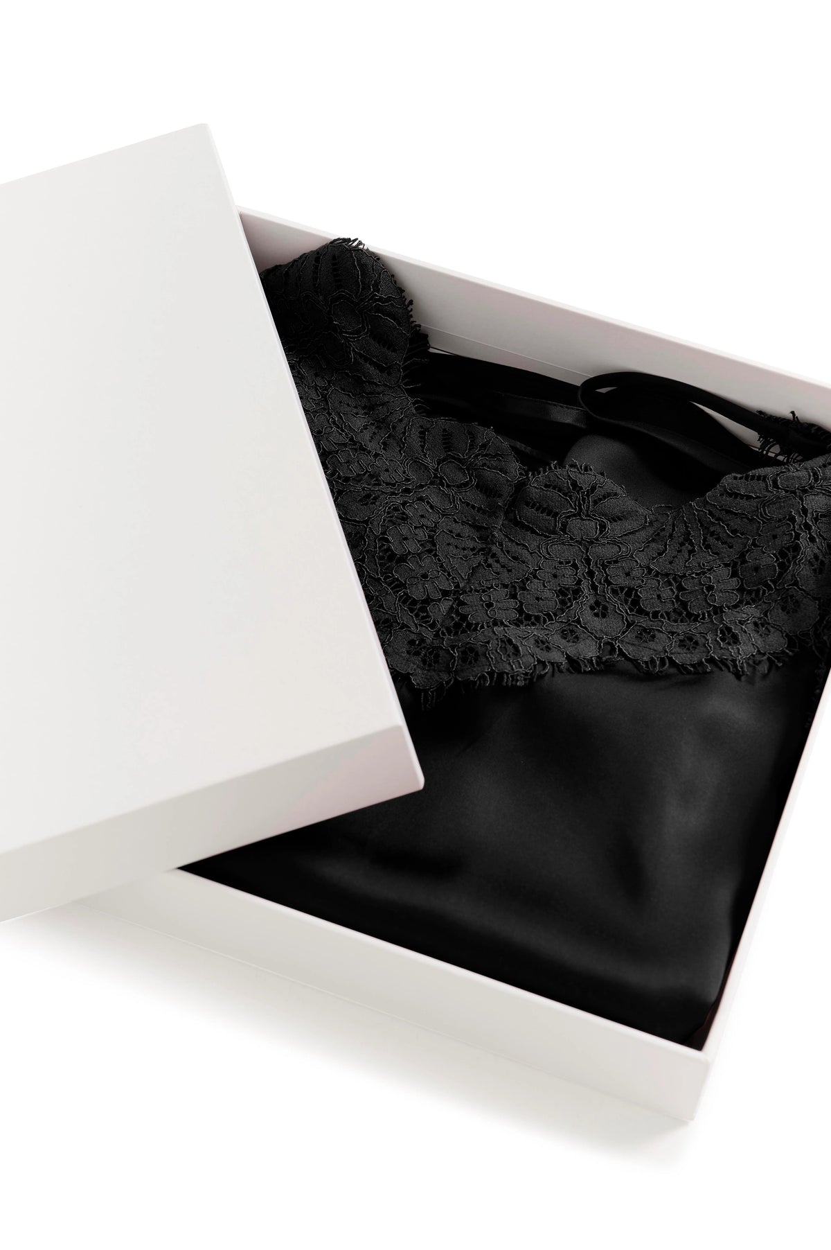 Black lace-trimmed satin camisole neatly folded in a white gift box