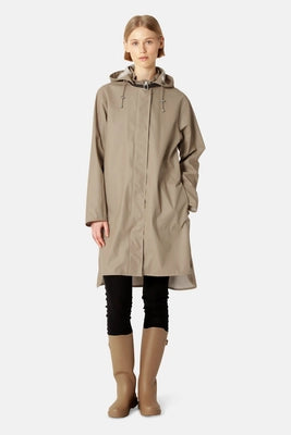 Ilse Jacobsen RAIN71 wheat hooded raincoat in taupe, worn with black leggings and beige boots.