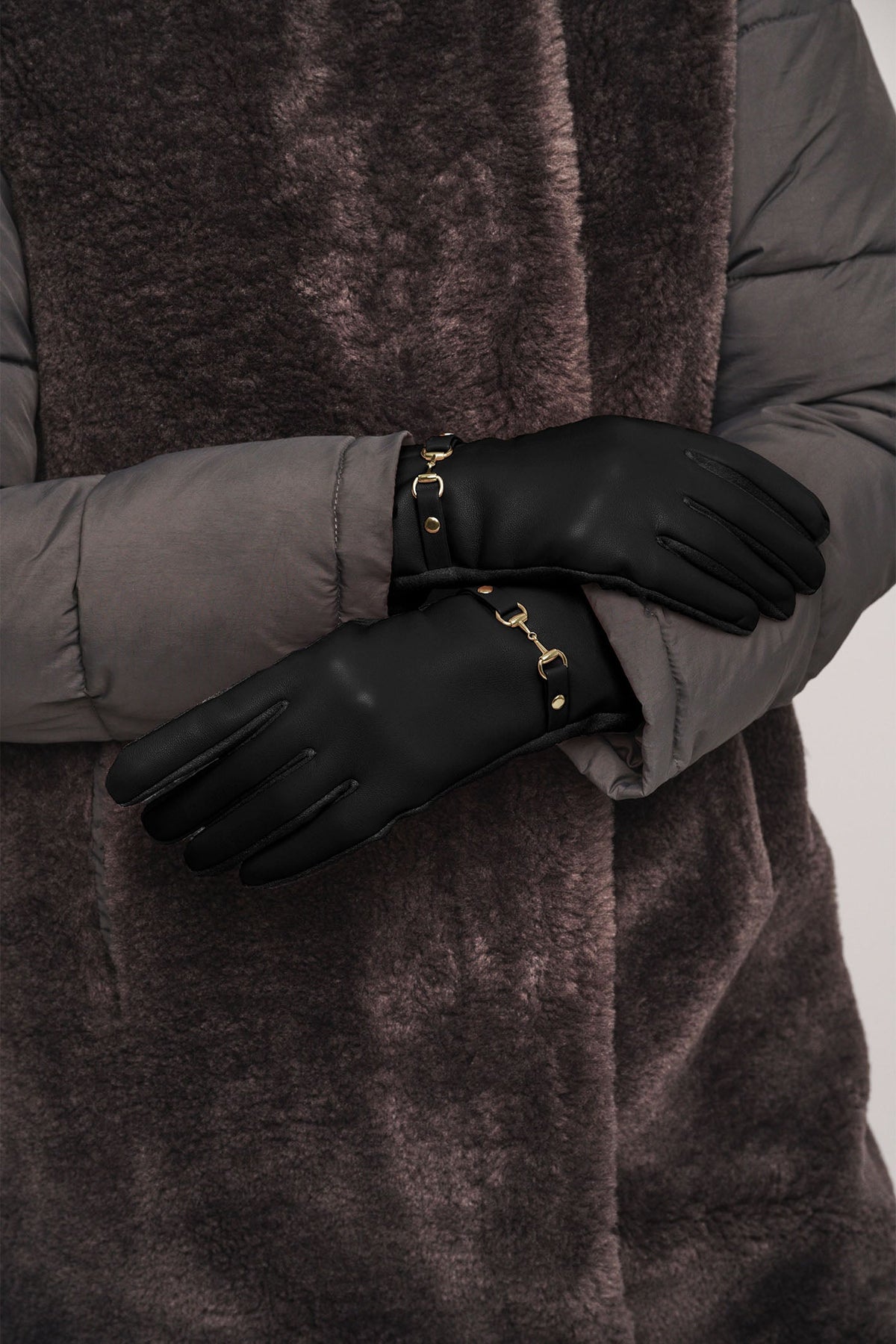 Black leather gloves with gold horsebit hardware detail worn with grey puffer jacket
