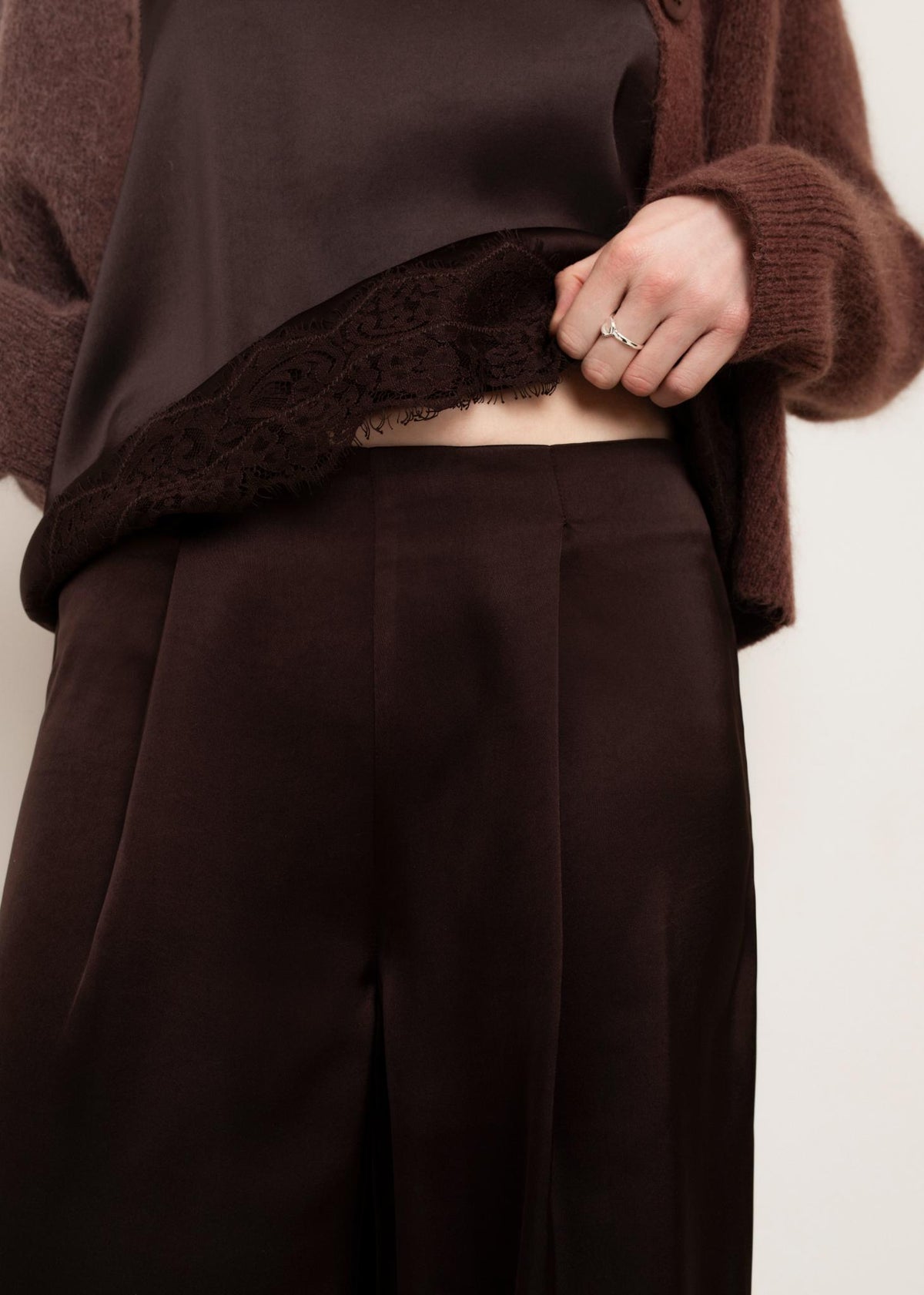 Close-up detail of chocolate torte wide-leg trousers with satin finish and center crease