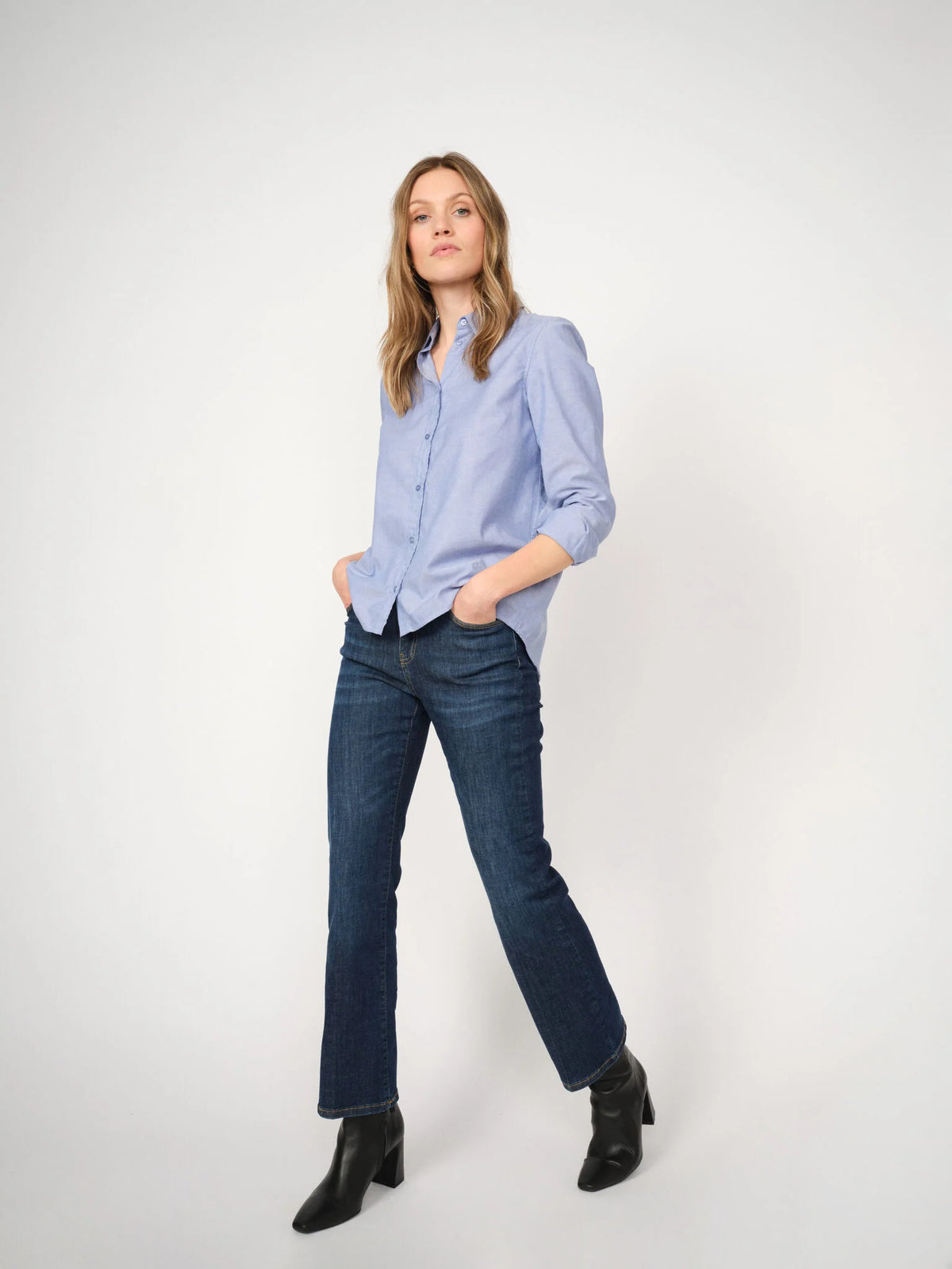 Dark blue straight-leg jeans worn with a light blue shirt and black ankle boots