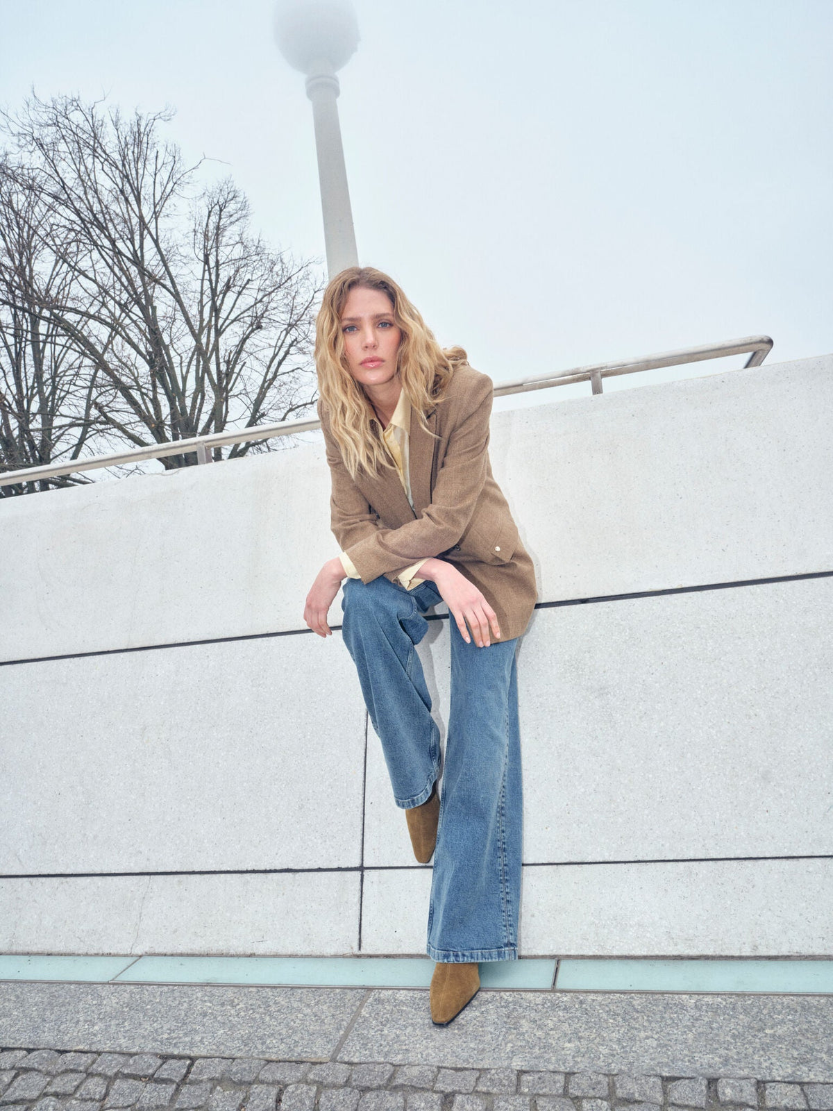Model wearing Mos Mosh Bethie Case Blazer in dark camel with wide-leg jeans outdoors