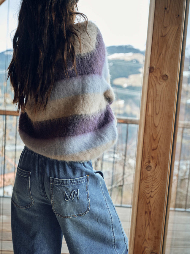 Fluffy striped knit sweater in purple and beige tones, worn with wide-leg jeans