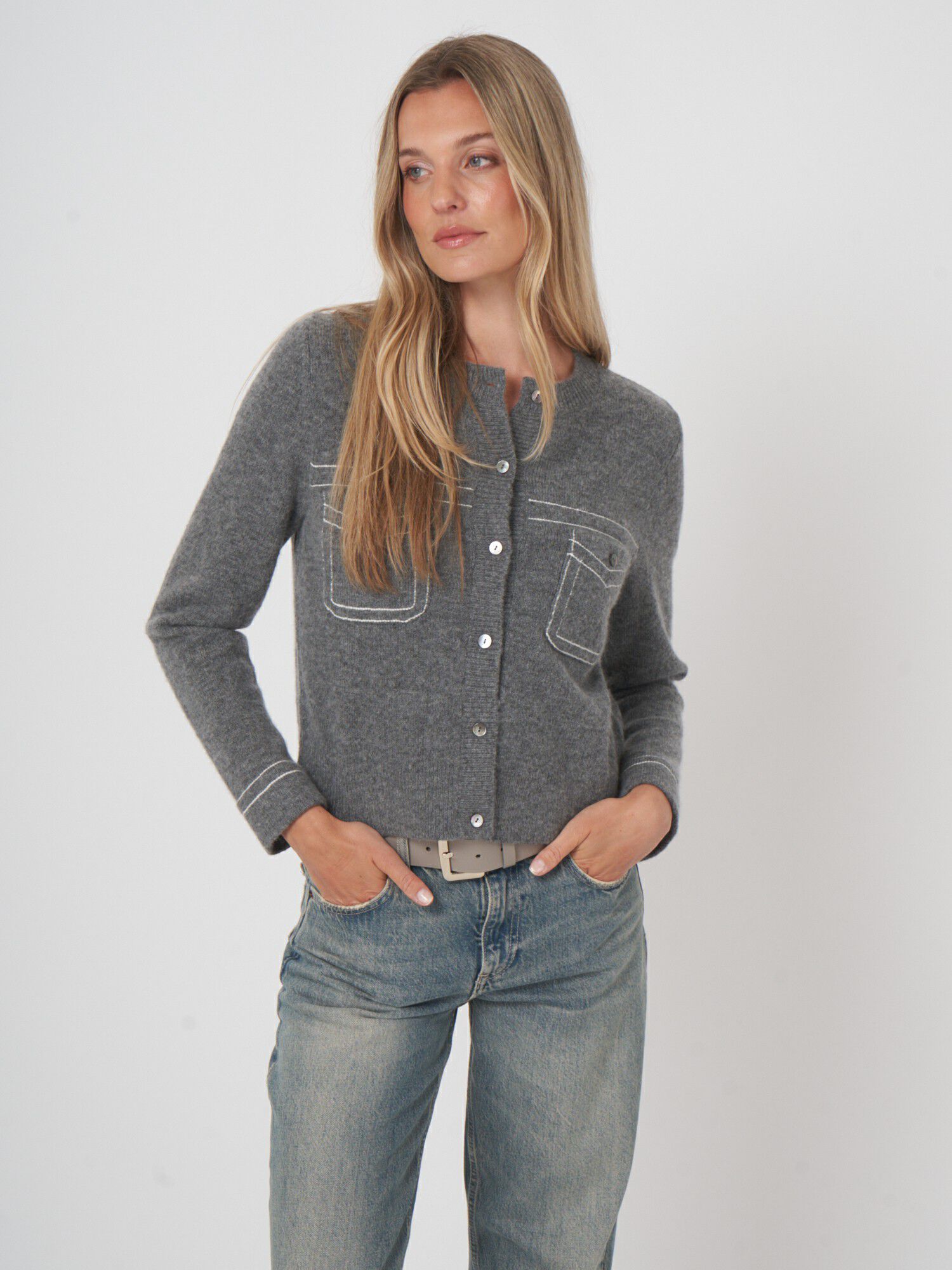 Woman wearing grey wool cashmere cardigan with white stitch detail and front pockets