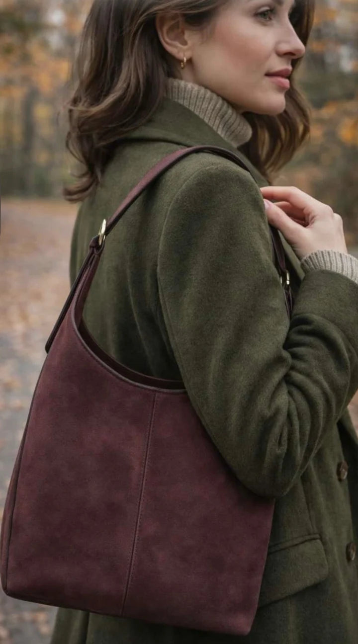 Risa Claude maroon suede shoulder bag with adjustable strap, worn by woman
